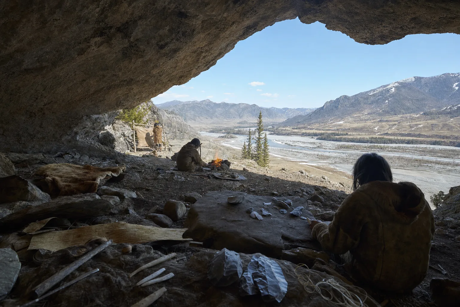 Realistic reconstruction of a small Middle Pleistocene family group beside a rock shelter in the Altai, working hides and stone tools by a fire